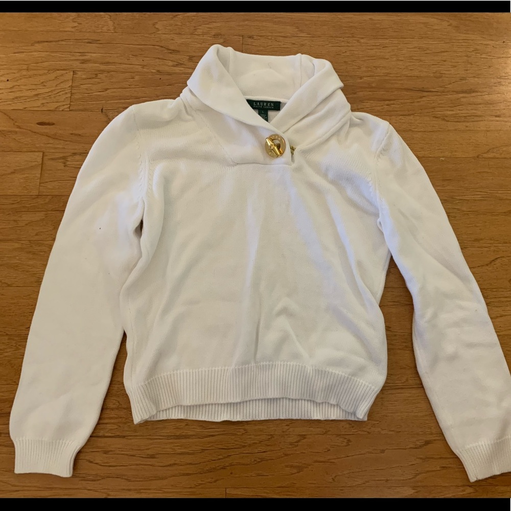 White sweater polo with gold buckle on neck.